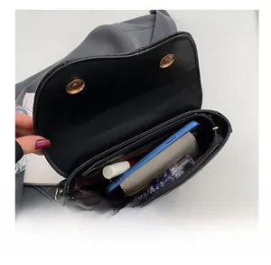 Interior view showing capacity of black leather saddle bag with phone, wallet and lipstick