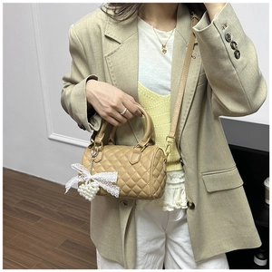 Quilted khaki Boston bag detail with white lace bow and pearl heart charm accents