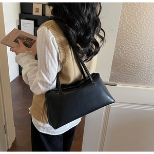 Model wearing a minimalist black glossy PU leather shoulder bag for a sleek commute look
