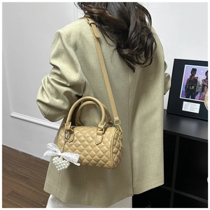 Close-up of khaki Boston bag featuring quilted lattice pattern and pearl heart charm