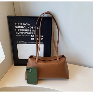 Brown faux leather shoulder bag with slim straps shown next to a smartphone for scale