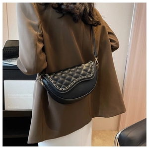 Detail showing quilted black faux leather saddle bag with gold chain trim on shoulder