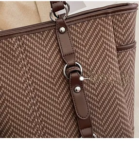 Detailed close-up of brown tote bag with herringbone weave and leather trim texture