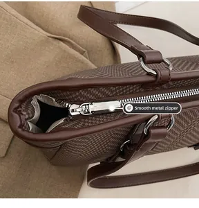 Detail of smooth metal zipper closure on brown herringbone tote bag for women