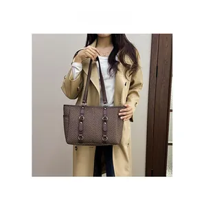 Close-up of brown herringbone tote bag featuring premium leather handles and elegant texture