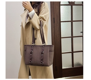 Detailed view of vintage brown herringbone tote bag with leather handles and silver rivets