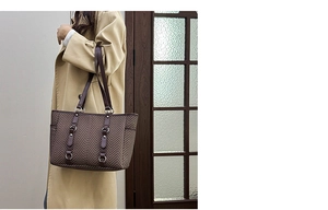 Detail of brown herringbone tote bag with leather straps and silver metal buckle accents