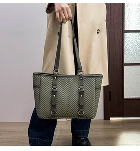 Detail of grey-green herringbone tote with olive leather trim and metallic ring accents
