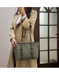 Detail of green herringbone tote bag with leather straps on model in trench coat