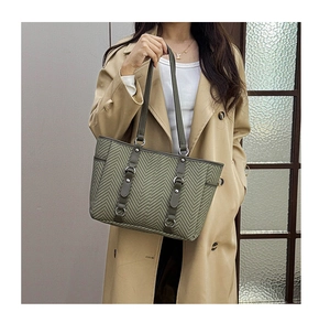 Detail of army green tote bag with herringbone texture and brown leather strap accents