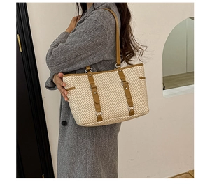 Detail of woven herringbone tote bag with khaki leather straps and silver metal hardware