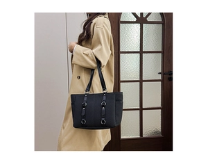 Detail of black tote bag with chevron texture and silver buckle on shoulder strap