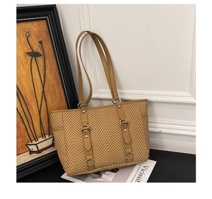 Detail of yellow woven tote bag with synthetic leather straps and silver metal rings