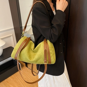 Detail of green suede tote bag with brown leather strap and gold hardware accents