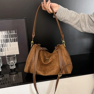 Macro shot of large brown suede hobo bag with gold hardware and smooth leather details