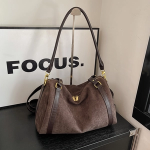 Detailed macro of dark brown suede handbag featuring reinforced leather straps and gold zippers