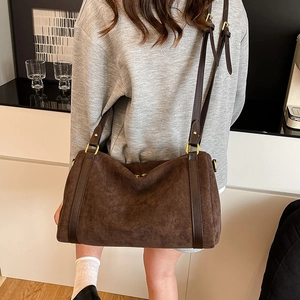 Detailed view of the dark brown suede texture and vintage gold buckle on a tote bag