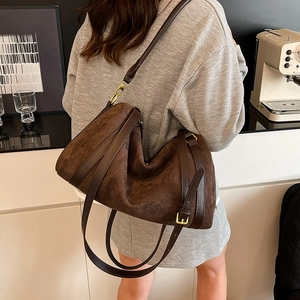 Detail of dark brown suede crossbody bag showing the golden buckle and adjustable strap