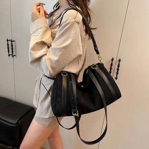 Detailed side view of a black suede hobo bag with gold hardware and leather trim accents