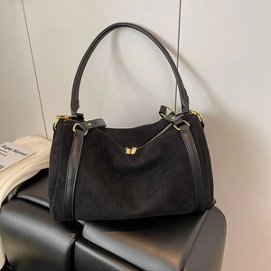 Detail of a black suede tote bag with leather straps and gold zipper on a bench