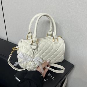 White quilted Boston handbag with pearl charms and gold hardware in a side-view angle