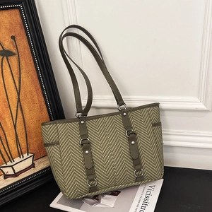 Green herringbone fabric tote bag with dark green straps and metallic ring details