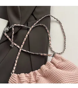 Close-up of pink crossbody bag with woven texture and adjustable metal chain strap