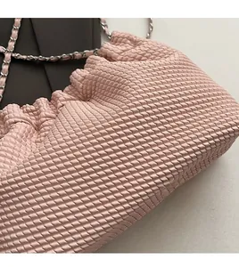 Close-up of pink cloud bag with woven texture and premium silver metal chain strap