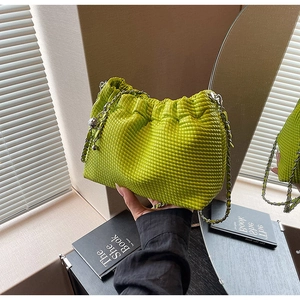 Detail of lime green woven texture handbag with silver chain and sphere charm