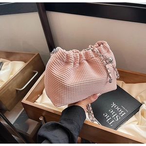 Close-up of pink woven cloud bag with silver chain strap and drawstring closure