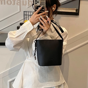 Mirror selfie showing the scale of a black pebbled leather bucket bag with silver charm