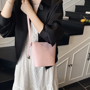 Detailed close-up of pink litchi grain leather bucket bag with heart metal charm detail