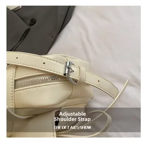 Detail of adjustable shoulder strap with silver buckle on cream faux leather handbag