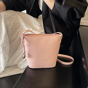 Detail of pink lychee leather bucket bag with gold logo and adjustable shoulder strap