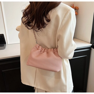 Detail of pink pleated crossbody bag with silver chain strap shown on a model