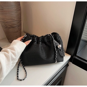 Detail of black pleated leather bag with silver metal chain and round ball pendant