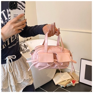 Detail of pink patent leather handbag featuring bow accents and twin flap pockets