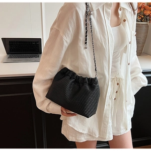 Detail view of black pleated shoulder bag with metal woven chain strap and soft leather texture