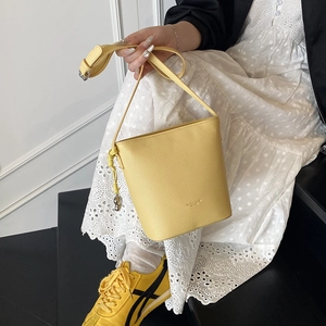 Detail of yellow pebbled leather bucket bag with metallic drawstring on side