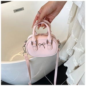 Detailansicht der kleinen rosa Ledertasche mit Metallschleife und Tragegriffen