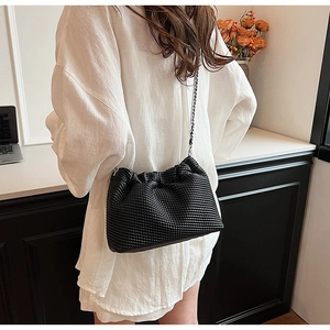 Close-up of black pleated cloud bag featuring textured woven finish and silver chain strap