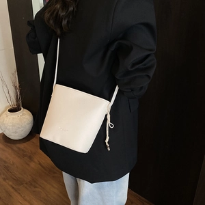Detail of off-white leather bucket bag with litchi texture and drawstring knot