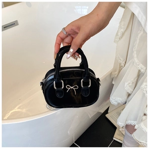 Detailansicht einer schwarzen Mini-Handtasche aus Leder mit silberner Schleife und Griffen