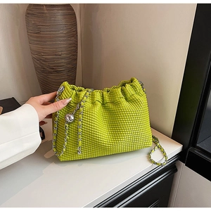 Detail of bright apple green woven pleated shoulder bag with silver chain and metal ball