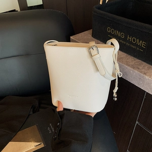 Detail of white bucket bag featuring pebble leather texture and adjustable silver buckle