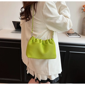 Detail of bright green shoulder bag with pleated texture and silver chain strap