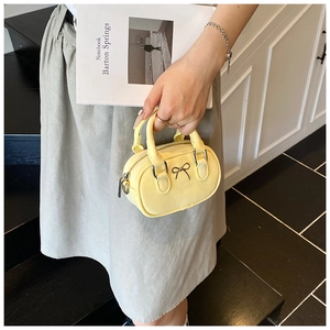 Detailansicht der gelben Mini-Handtasche mit Metalleffekt-Schleife und Lackleder