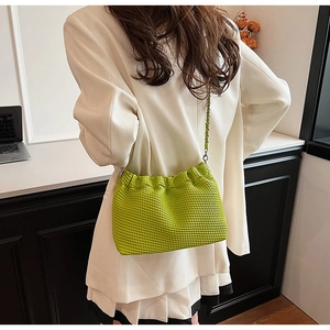 Detail of green quilted crossbody cloud bag featuring a stylish silver metal chain strap