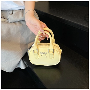 Detailansicht der gelben Mini-Handtasche mit silberner Schleife und Reißverschluss