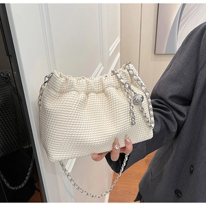 Close-up of cream white pleated shoulder bag featuring textured fabric and silver chain ball